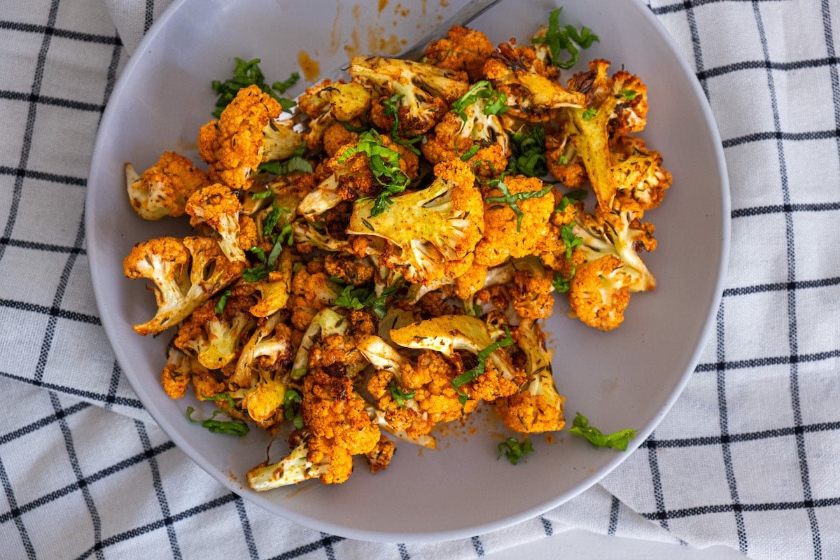cauliflower on a white plate with blue and white tablecloth
