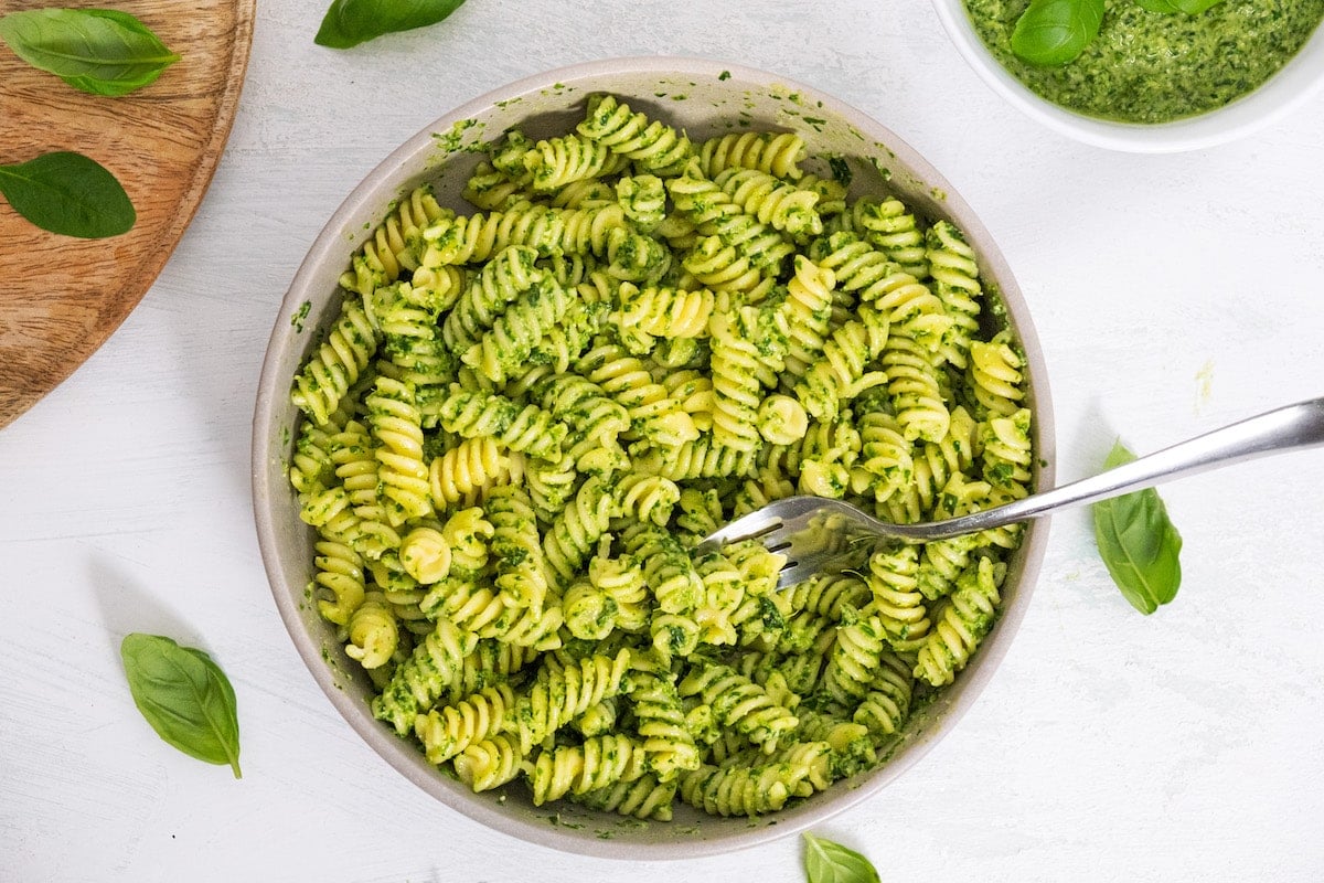 spinach pesto with pasta in white bowl