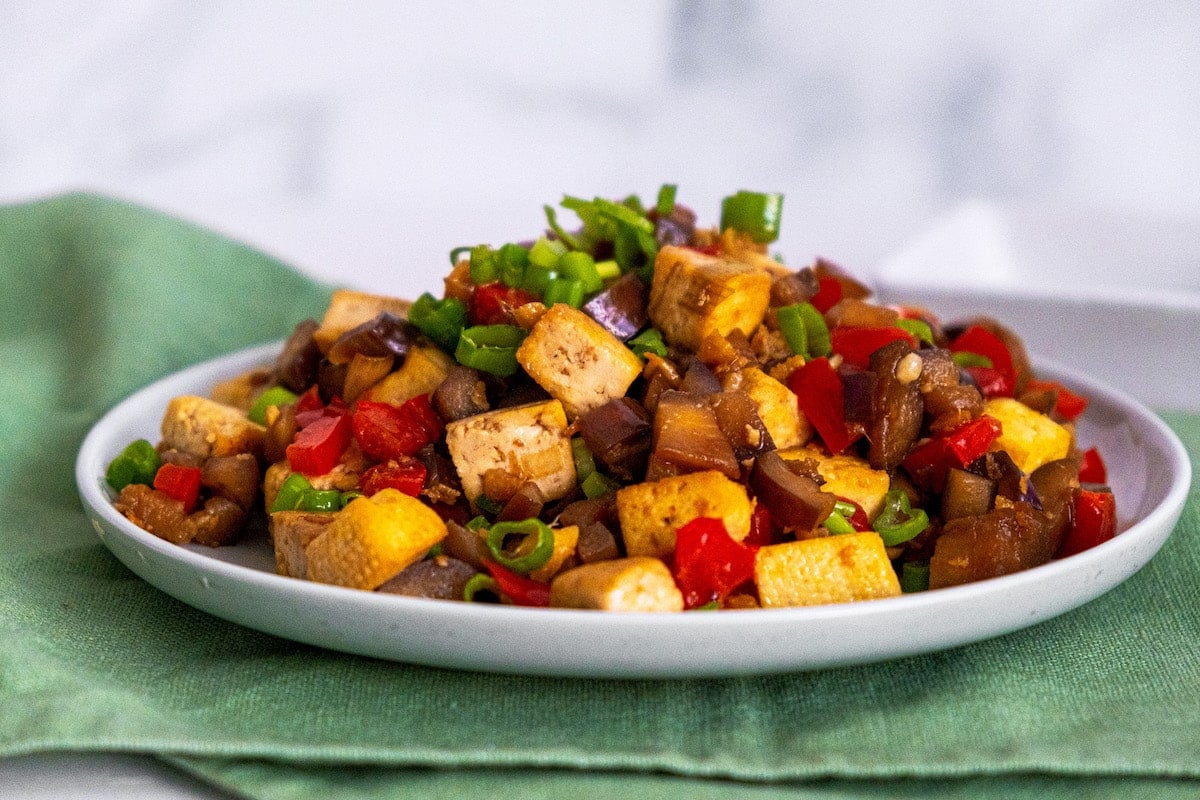 tofu and eggplant on a white plate with scallions